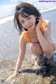 A woman in an orange bikini sitting in the water.