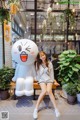 A woman sitting on a bench next to a giant stuffed animal.