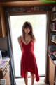 A woman in a red dress standing in front of a window.