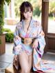 A woman in a blue kimono sitting on a bench.