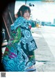 A woman in a colorful kimono standing on a sidewalk.