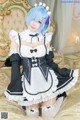 A woman in a maid outfit sitting on a bed.