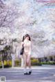 A woman in a white lingerie standing in front of a tree.