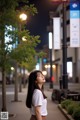 A woman standing in the middle of a city street at night.