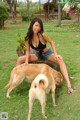 A woman sitting on top of a tree stump next to a dog.