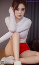 a woman in a white top and red shorts sitting on a table