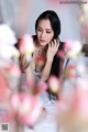 A woman in a white dress sitting on a bed of flowers.