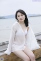 A woman in a white shirt sitting on a wooden dock.