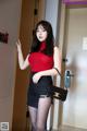 A woman in a red top and black skirt posing for a picture.