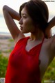 A woman in a red dress standing on a beach.