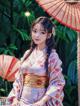 A woman in a kimono sitting under an umbrella.