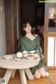 A woman in a green kimono sitting at a table with a bowl of food.