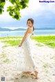 A woman in a white dress standing on a beach.