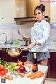 A woman in a kitchen preparing food on a counter.