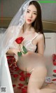 A woman in a white lingerie holding a red rose.