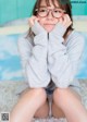 A young woman wearing glasses sitting on the floor.