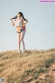 A woman standing on top of a grass covered hill.