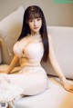A woman in a white lingerie sitting on a couch.
