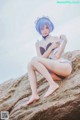 A woman in a bikini sitting on a rock.