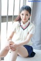 A young woman sitting on the floor in a school uniform.