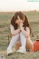 A young woman sitting on the ground in a field.