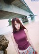 A woman standing on a beach next to a bridge.