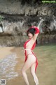 A woman in a red and white bikini standing in the water.