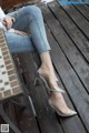 A woman sitting on a wooden bench wearing a pair of silver shoes.