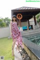 A woman in a pink dress standing next to a swimming pool.