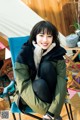 A woman sitting in a chair in front of a tent.