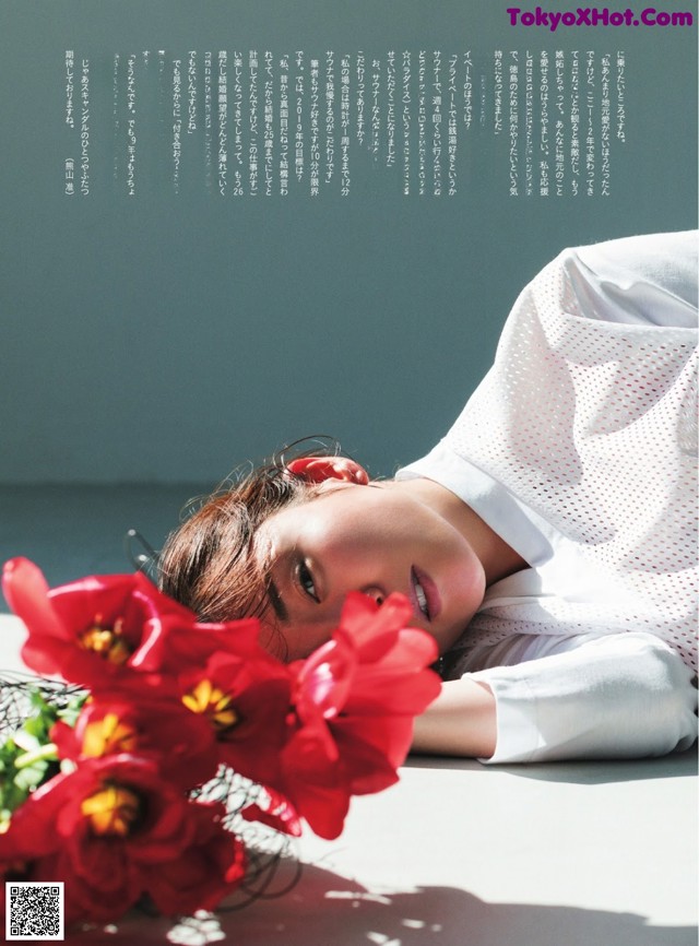 A woman laying on the ground next to a bunch of flowers.