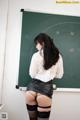 A woman in a skirt and stockings standing in front of a blackboard.