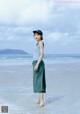 A woman standing on a beach next to the ocean.