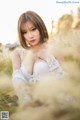 A woman in a white dress sitting in a field of tall grass.