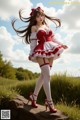 A woman in a red and white dress standing on a rock.