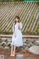 A woman in a blue dress standing on a stone wall.