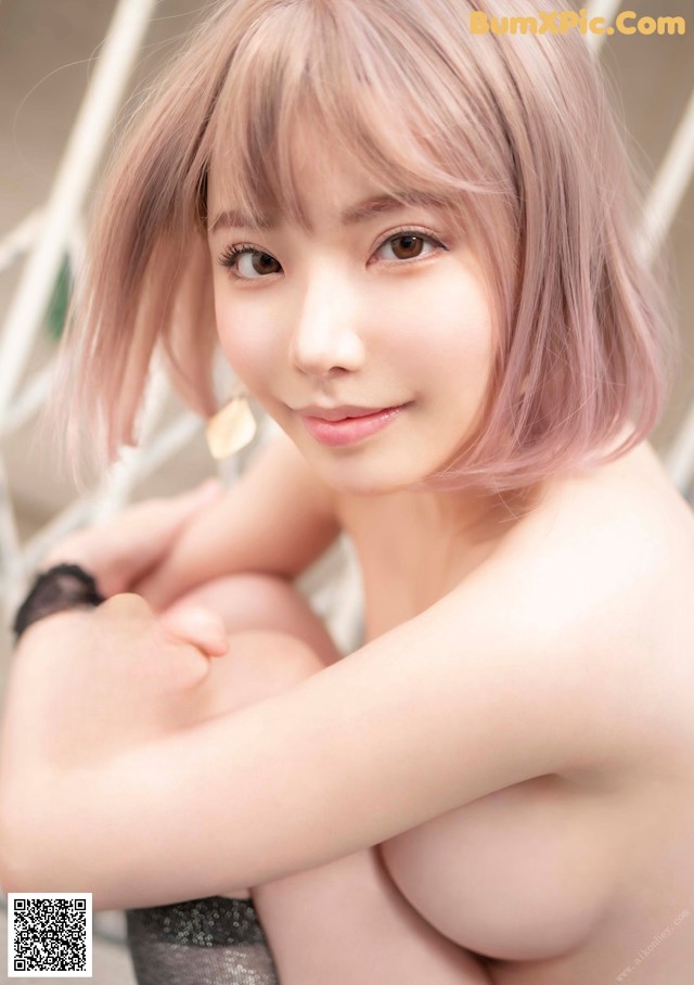 A woman with pink hair is posing for the camera.