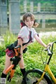 A woman in a school uniform is posing with a bike.